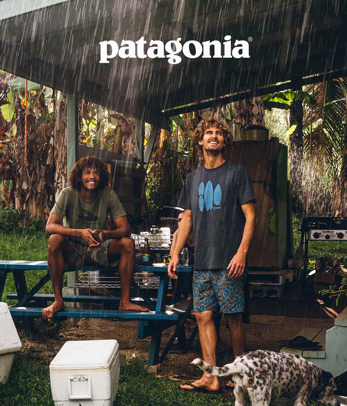 Two guys smiling while they wait out a tropical storm in an outdoor kitchen.